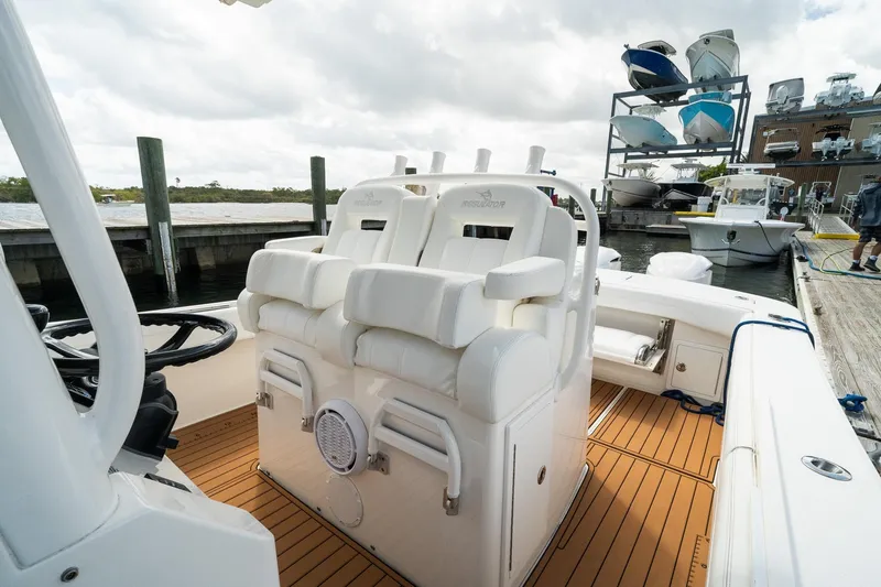 Slide: The Image of 2020 Regulator 31 boat interior with white seating and wooden deck at a marina. - 46