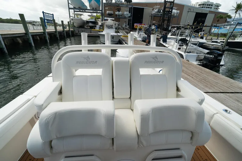 Slide: The Image of 2020 Regulator 31 boat with white cushioned seats at a marina dock. - 50