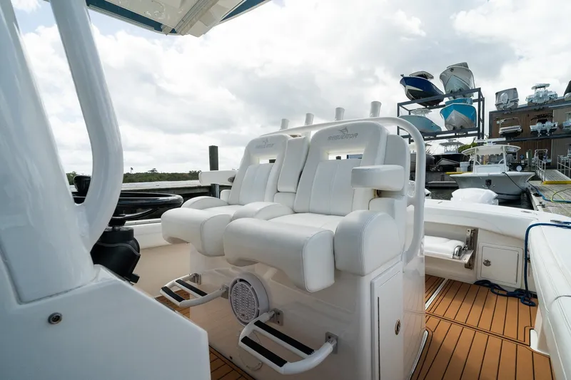 Slide: The Image of 2020 Regulator 31 boat interior with white seating and wooden deck at a marina. - 52