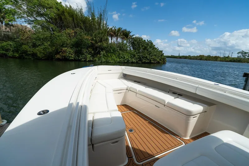 Slide: The Image of 2020 Regulator 31 boat interior with white seating and wooden deck, near lush greenery and water. - 56