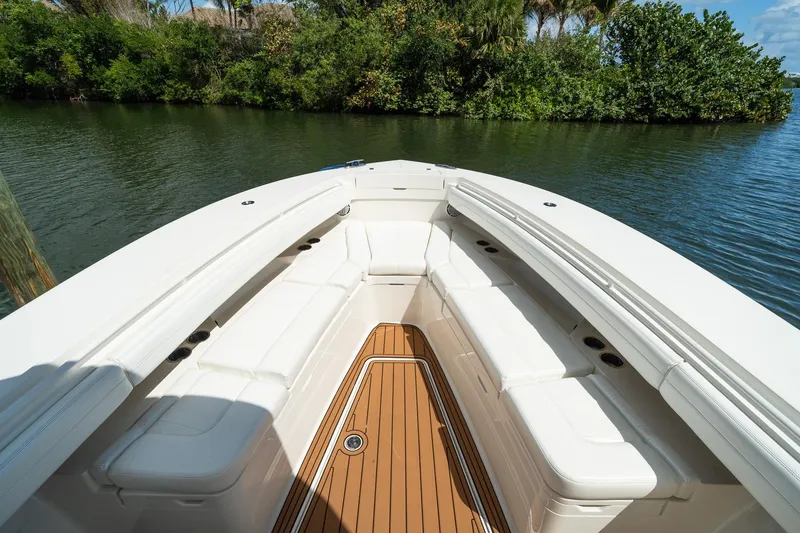 Slide: The Image of 2020 Regulator 31 boat with white seating and teak deck, docked by lush greenery. - 59