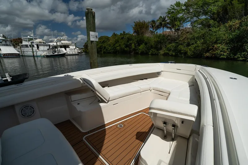 Slide: The Image of 2020 Regulator 31 boat with white seating and wooden deck, docked near lush greenery. - 62