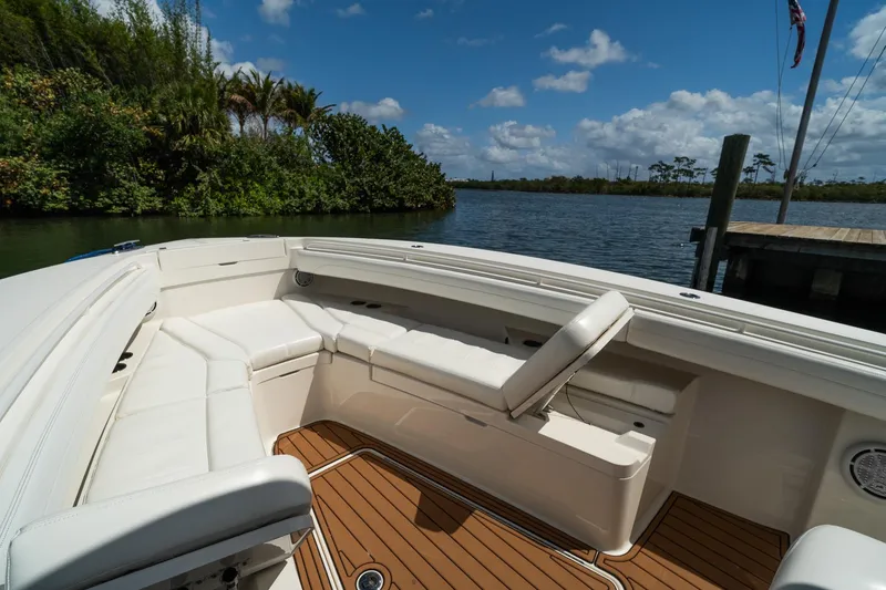 Slide: The Image of 2020 Regulator 31 boat interior with white seating and wooden deck, docked by a scenic river. - 63