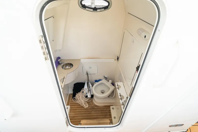 Slide: The Image of 2020 Regulator 31 boat interior with compact bathroom, featuring a toilet and sink. - 66