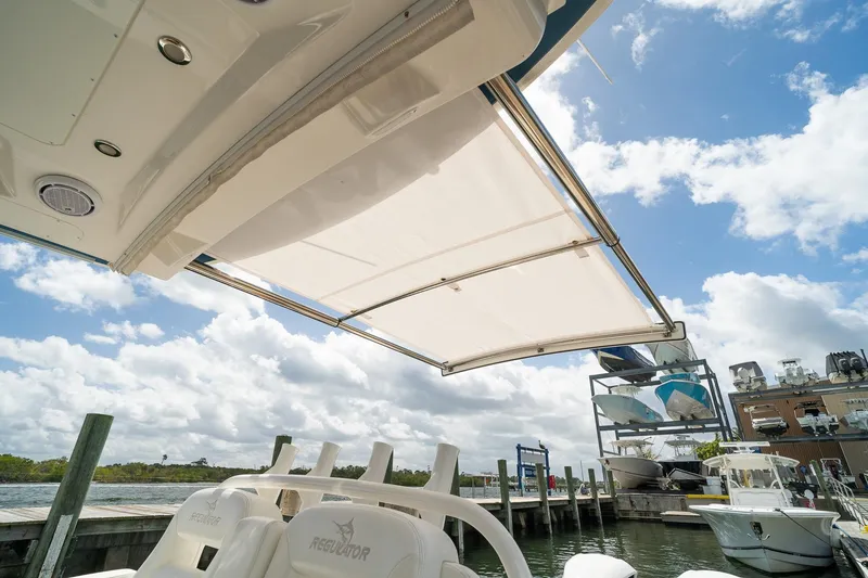 Slide: The Image of 2020 Regulator 31 boat with extended canopy at marina under blue sky. - 68