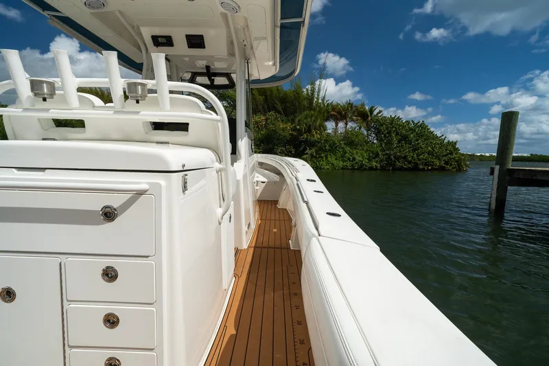 Slide: The Image of 2020 Regulator 31 boat with sleek white deck and rod holders, docked by lush greenery. - 9
