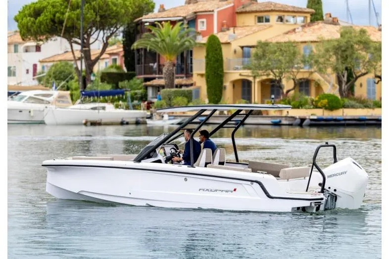 The Image of 2027 Axopar 22 T-Top boat cruising near waterfront homes. - 1