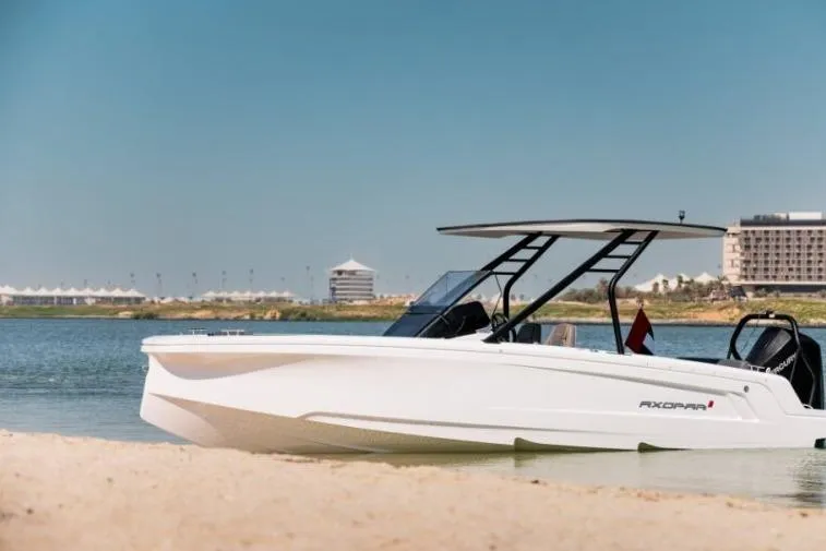 Slide: The Image of 2027 Axopar 22 T-Top boat docked on a serene beach with clear skies. - 3