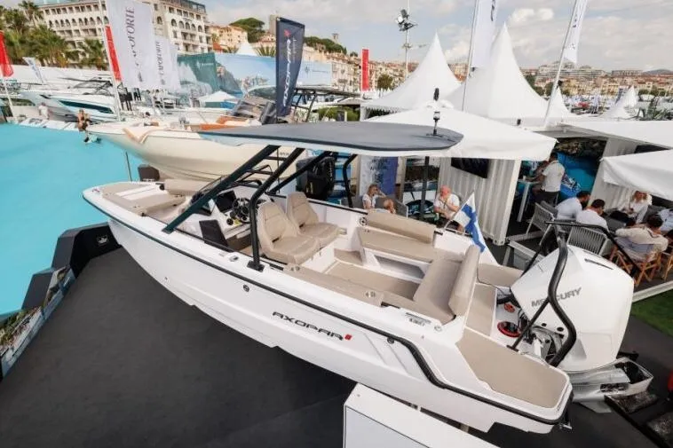 Slide: The Image of 2027 Axopar 22 T-Top boat displayed at a marine exhibition with elegant seating and Mercury engine. - 9