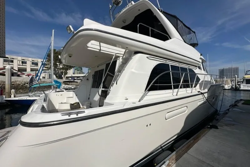 Slide: The Image of 1999 Bayliner 5788 Pilot House Motoryacht docked at marina under clear blue sky. - 2