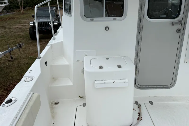 Slide: The Image of 2005 Osprey 28 Long Cabin boat deck with steps and door, parked on land. - 5