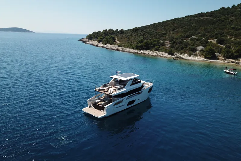 Slide: The Image of Luxury Absolute Navetta 70 yacht cruising near scenic coastline, 2026 model. - 1
