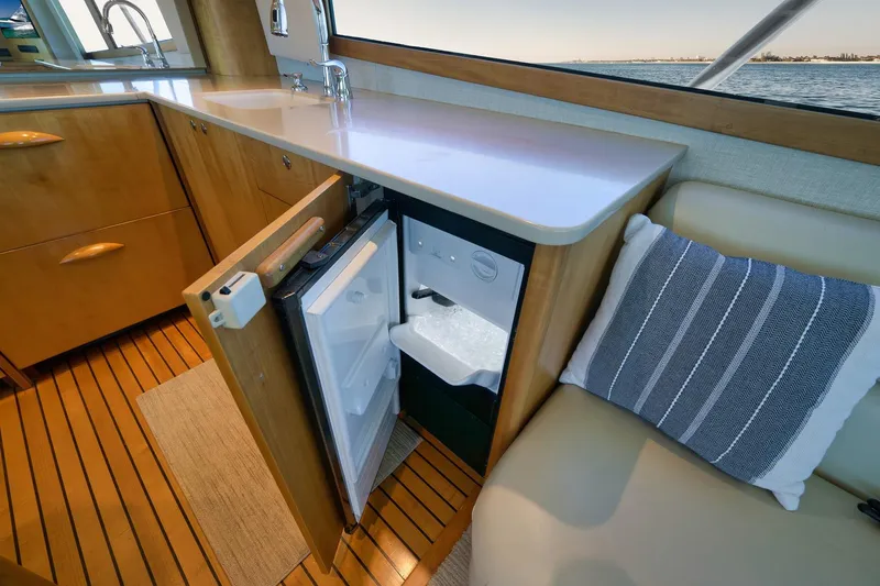 Slide: The Image of 2003 Weaver Custom Sportfish interior with open mini fridge, wooden cabinetry, and striped cushion. - 22