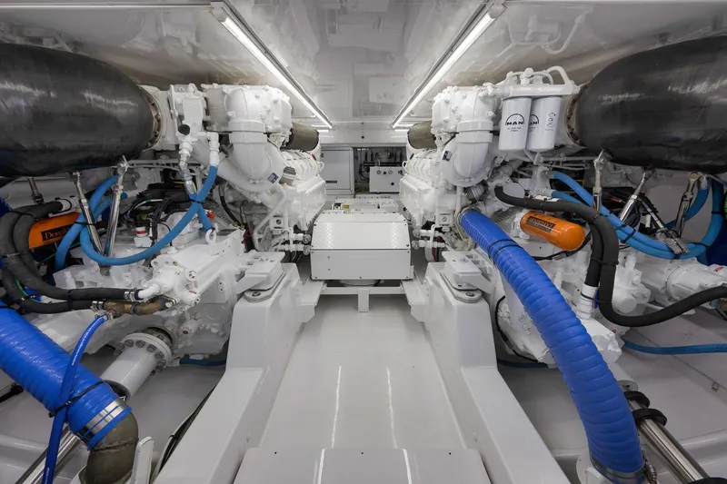 Slide: The Image of Engine room of a 2003 Weaver Custom Sportfish boat, featuring dual engines and blue hoses. - 47