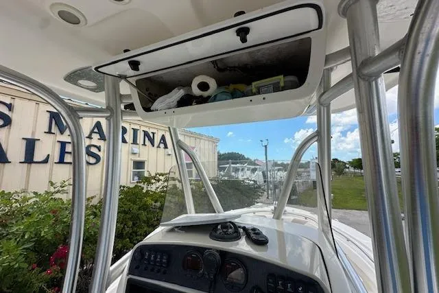 Slide: The Image of 2014 Pioneer 222 Sportfish boat dashboard with overhead storage, marina background. - 18