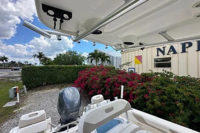 Slide: The Image of 2014 Pioneer 222 Sportfish boat with outboard motor, near lush greenery and building. - 21