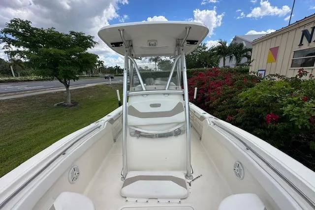 Slide: The Image of 2014 Pioneer 222 Sportfish boat with T-top, docked near lush greenery and clear skies. - 7