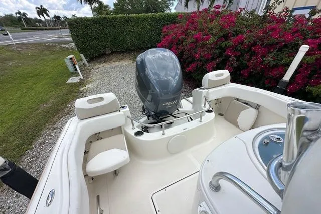 Slide: The Image of 2014 Pioneer 222 Sportfish boat with outboard motor, surrounded by lush greenery and flowers. - 9