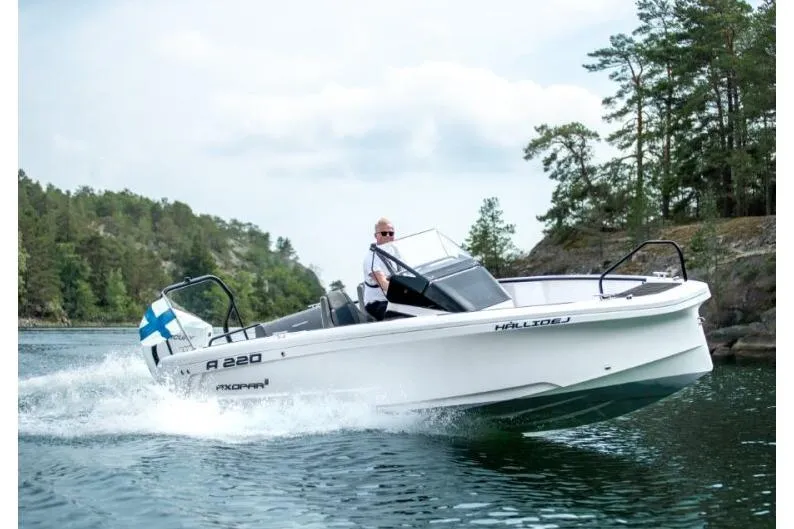 The Image of 2027 Axopar 22 Spyder cruising on a scenic lake with lush greenery. - 1