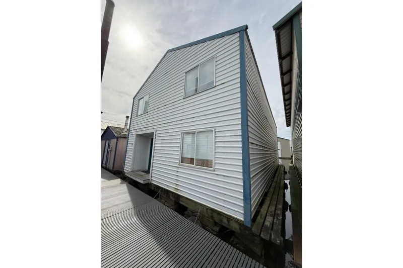 The Image of White boathouse with blue trim, Hargraves model, built in 2008, under a cloudy sky. - 1