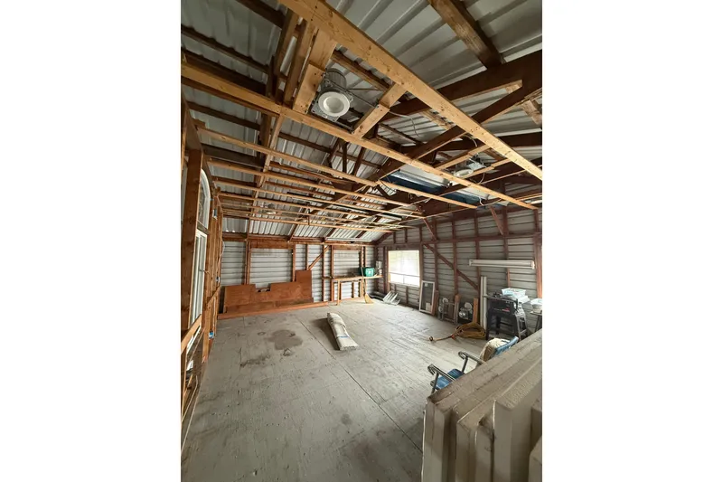Slide: The Image of Interior of a 2008 Custom Hargraves boathouse with exposed wooden beams and stored materials. - 7
