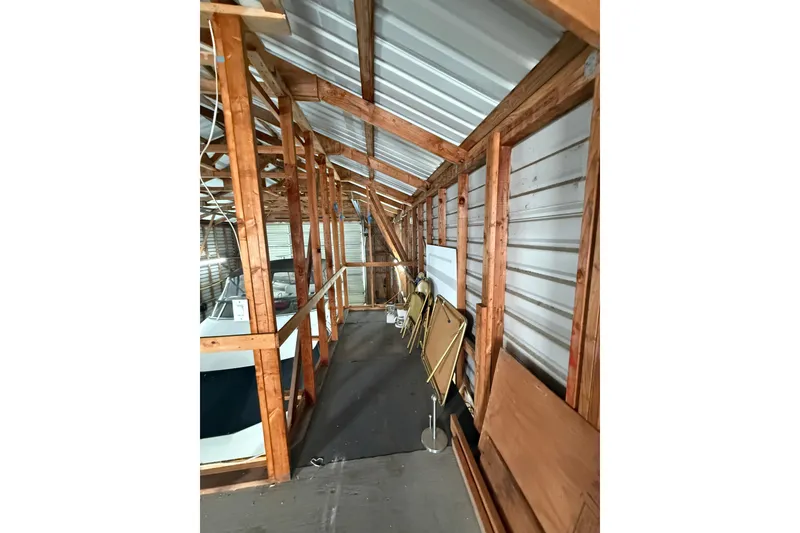 Slide: The Image of Interior of a wooden Hargraves boathouse, featuring stored chairs and a boat, built in 2008. - 9