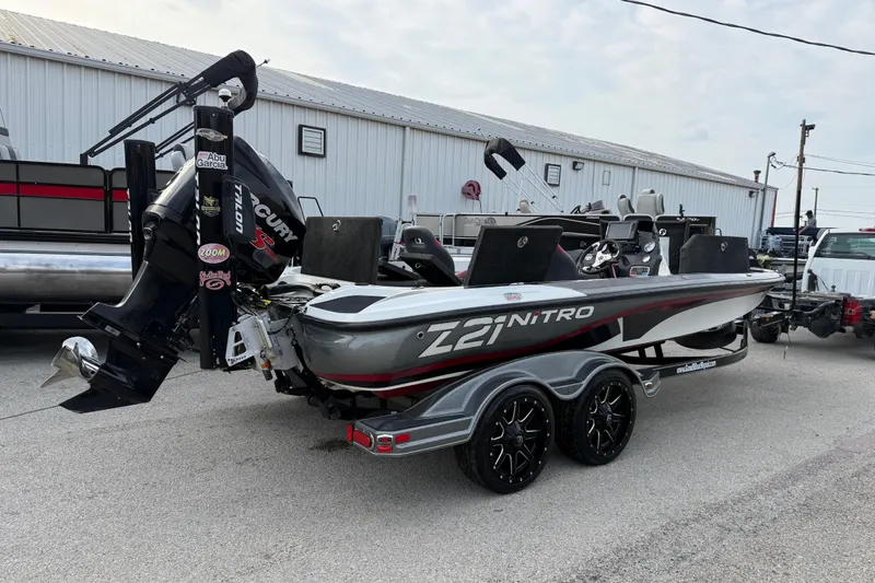 Slide: The Image of 2016 Nitro Z21 boat with Mercury engine on trailer, parked near a warehouse. - 10
