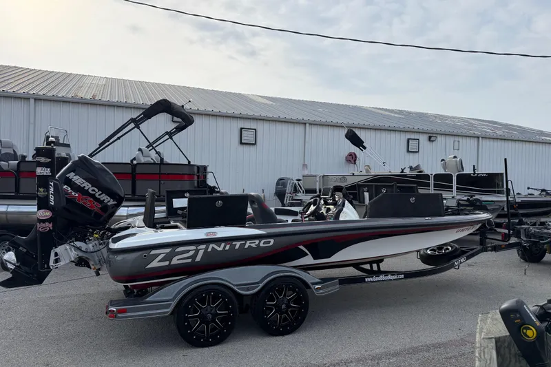 Slide: The Image of 2016 Nitro Z21 boat with Mercury engine on trailer, parked near metal building. - 11