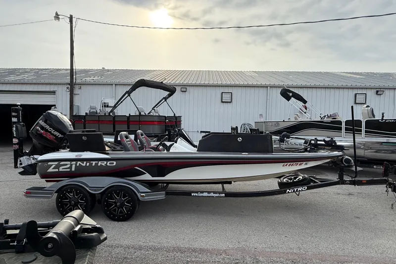 Slide: The Image of 2016 Nitro Z21 boat with trailer, parked outdoors near a metal building. - 12