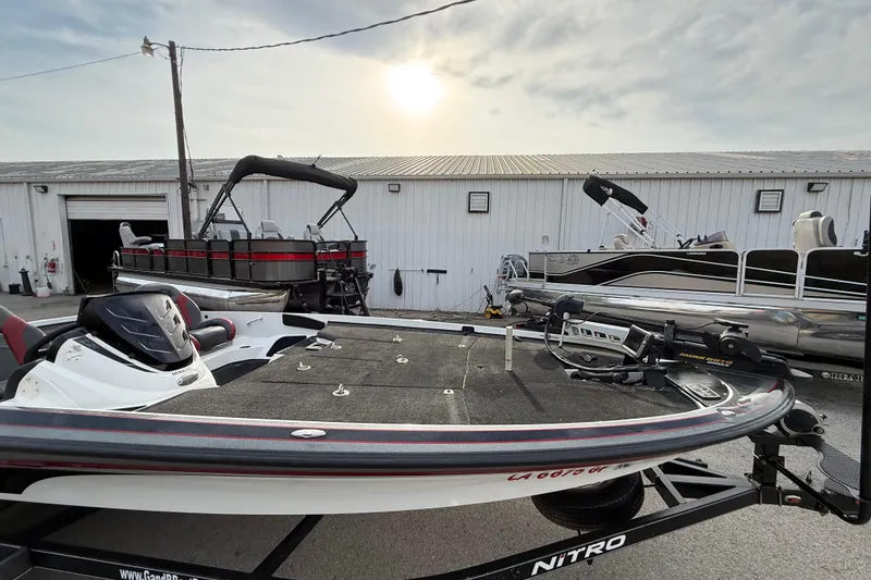 Slide: The Image of 2016 Nitro Z21 boat on trailer, parked near other boats, under a cloudy sky. - 14