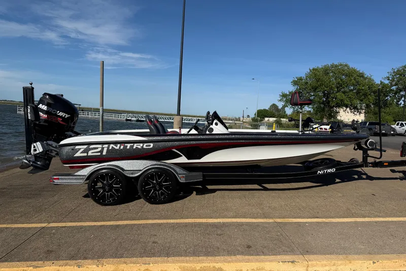 Slide: The Image of 2016 Nitro Z21 boat on trailer by the water, featuring a Mercury engine. - 31