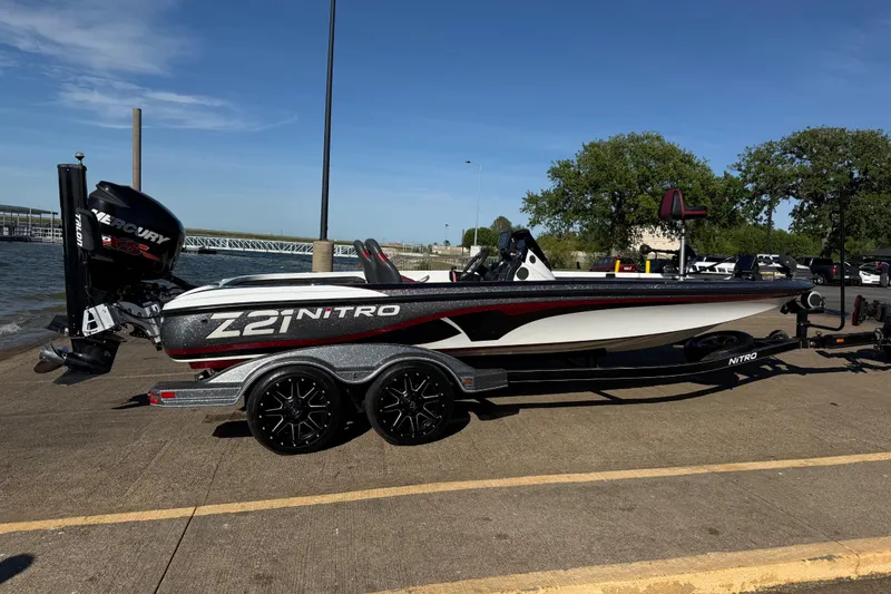Slide: The Image of 2016 Nitro Z21 boat on trailer by the water, featuring a Mercury engine. - 32