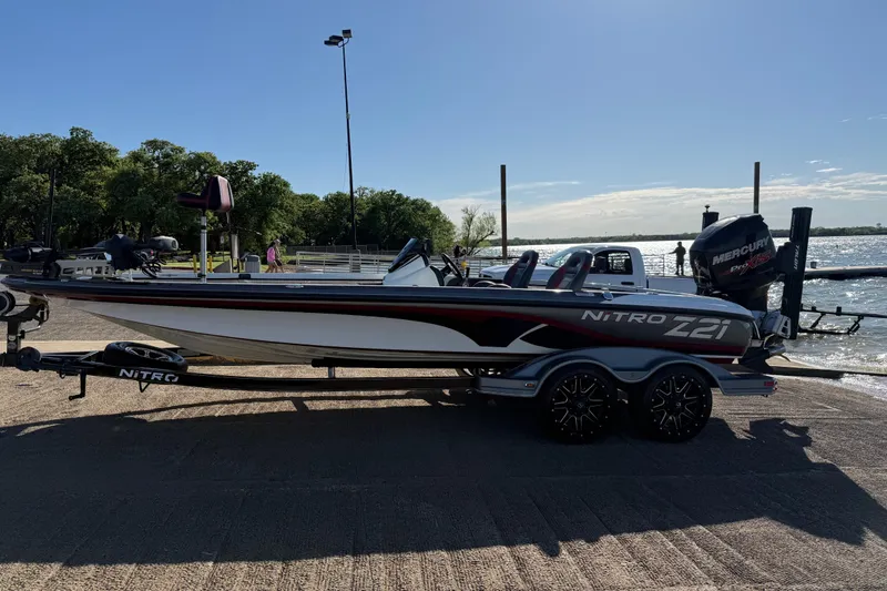 Slide: The Image of 2016 Nitro Z21 boat on trailer by lakeside, featuring sleek design and Mercury engine. - 49