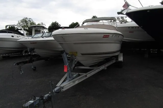 Slide: The Image of 2000 Sea Ray 210 Signature boat on trailer, parked among other boats. - 25