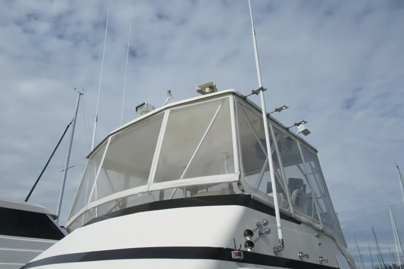 Slide: The Image of 1990 Viking 38 Convertible boat with antennas and enclosed flybridge under cloudy sky. - 11