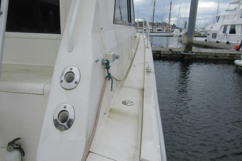 Slide: The Image of 1990 Viking 38 Convertible yacht docked at marina, showcasing side deck and fittings. - 24
