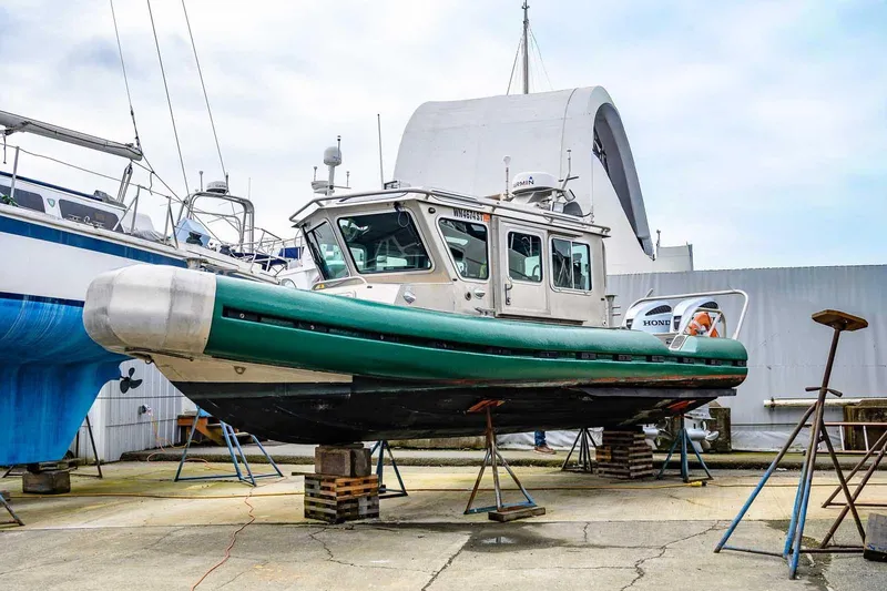 The Image of 2004 SAFE Boats Defender on dry dock, green hull, maintenance setting. - 1