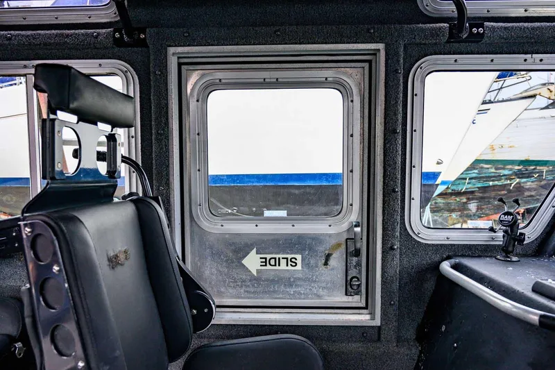 Slide: The Image of Interior view of a 2004 SAFE Boats Defender, featuring a sliding window and seating. - 22