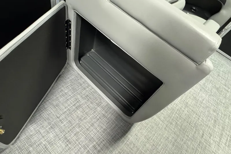 Slide: The Image of 2026 Sun Tracker Party Barge 20 DLX storage compartment with open door, gray interior. - 16