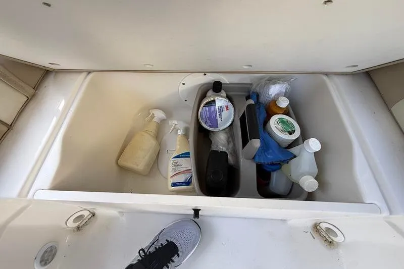 Slide: The Image of Storage compartment of 2017 NauticStar 243DC Sport Deck with cleaning supplies and shoe visible. - 10