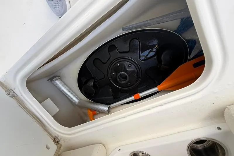 Slide: The Image of Storage compartment of 2017 NauticStar 243DC Sport Deck with paddle and accessories. - 11