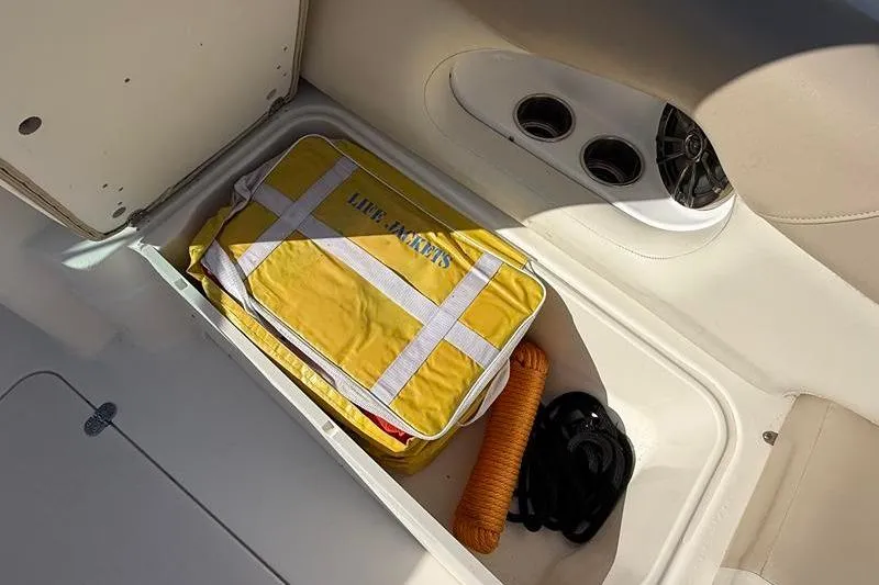 Slide: The Image of Storage compartment in 2017 NauticStar 243DC Sport Deck with life jackets and rope. - 22