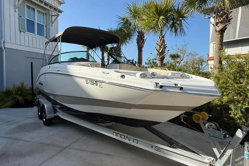 Slide: The Image of 2017 NauticStar 243DC Sport Deck boat on trailer, parked near palm trees. - 5