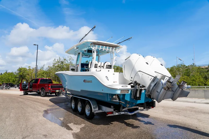 Slide: The Image of 2024 Crevalle 33 CSF boat on trailer, parked near red truck under blue sky. - 10