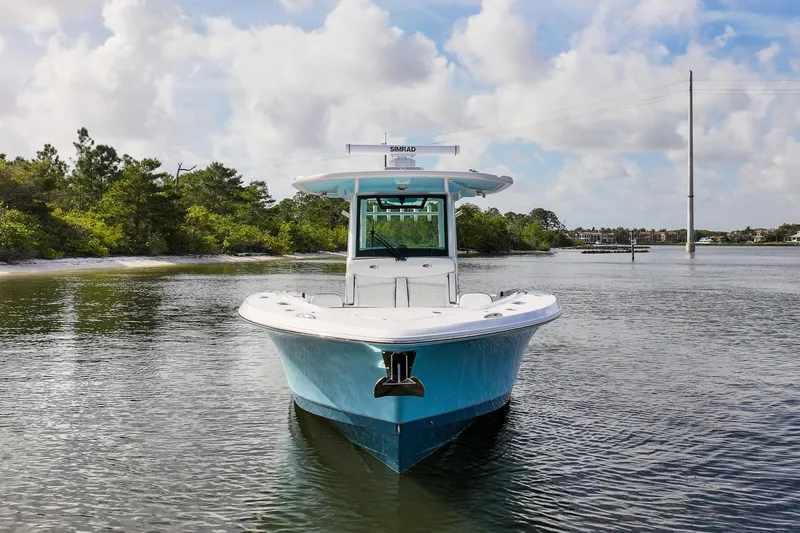 Slide: The Image of 2024 Crevalle 33 CSF boat on calm water, surrounded by lush greenery. - 2