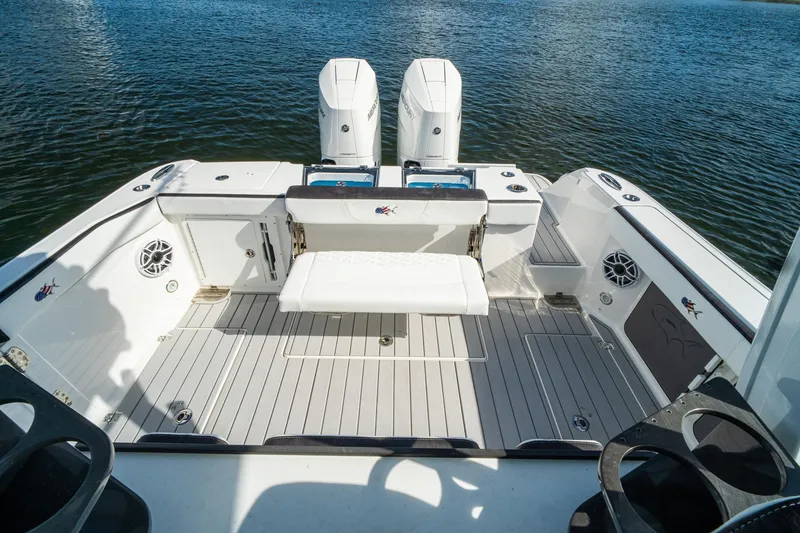 Slide: The Image of 2024 Crevalle 33 CSF boat deck with twin engines and seating, on calm water. - 24