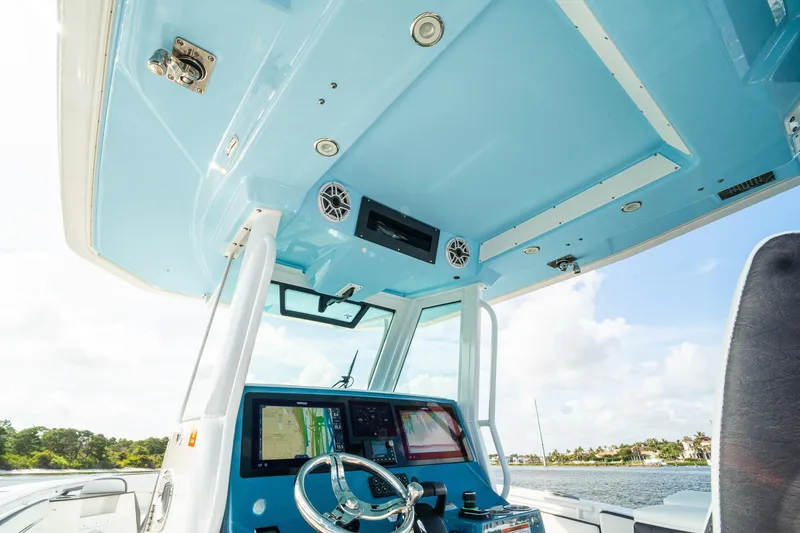 Slide: The Image of 2024 Crevalle 33 CSF boat helm with modern navigation equipment and blue canopy. - 53