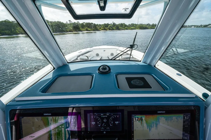 Slide: The Image of 2024 Crevalle 33 CSF boat dashboard with navigation screens on a calm waterway. - 56