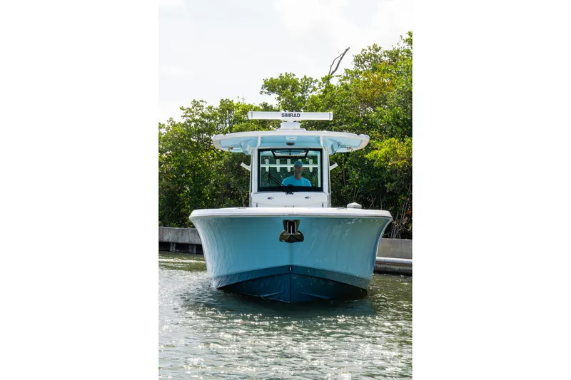 Slide: The Image of 2024 Crevalle 33 CSF boat navigating through calm waters, surrounded by lush greenery. - 8