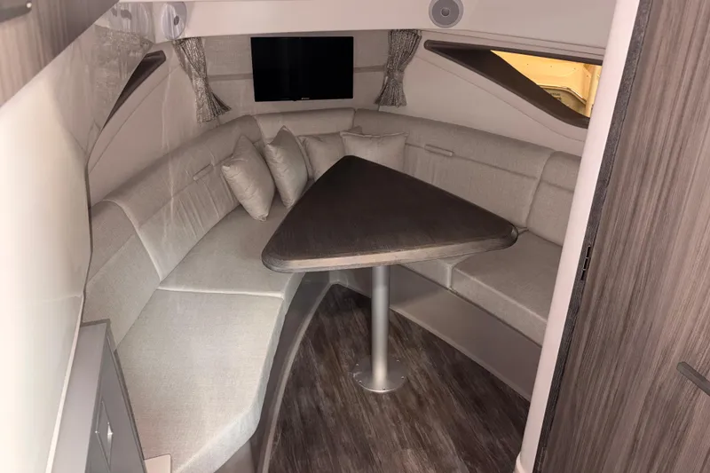 Slide: The Image of Interior of 2026 Sea Ray Sundancer 320, featuring a cozy seating area with a triangular table. - 18
